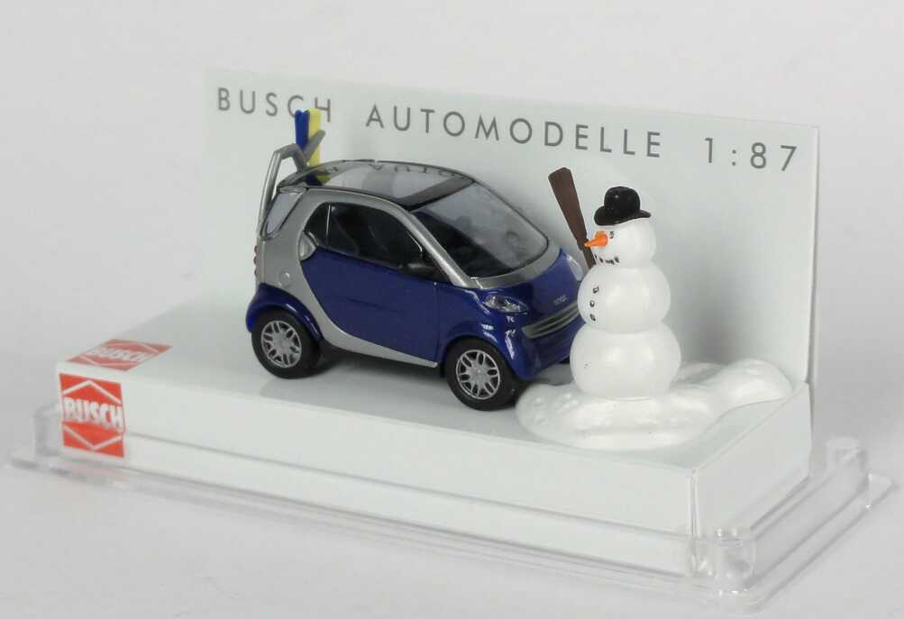 Foto 1:87 MCC Smart City-Coupé dunkelblau/silber mit Skiträger, Ski und Schneemann Busch 48918